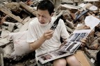 Парень смотрит семейный альбом, который нашел в щебне его старого дома, после землетрясения в Сычуани.   